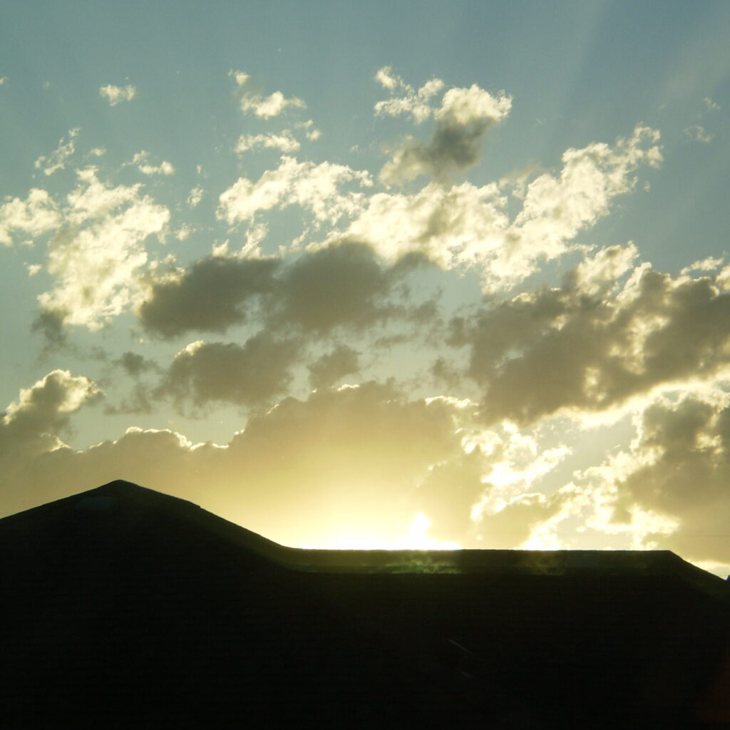 image of the sun shining over a rooftop in silhouette